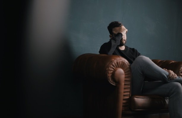 A man sitting alone on a couch, deep in thought